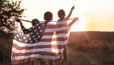 Kids holding a American flag at sunset