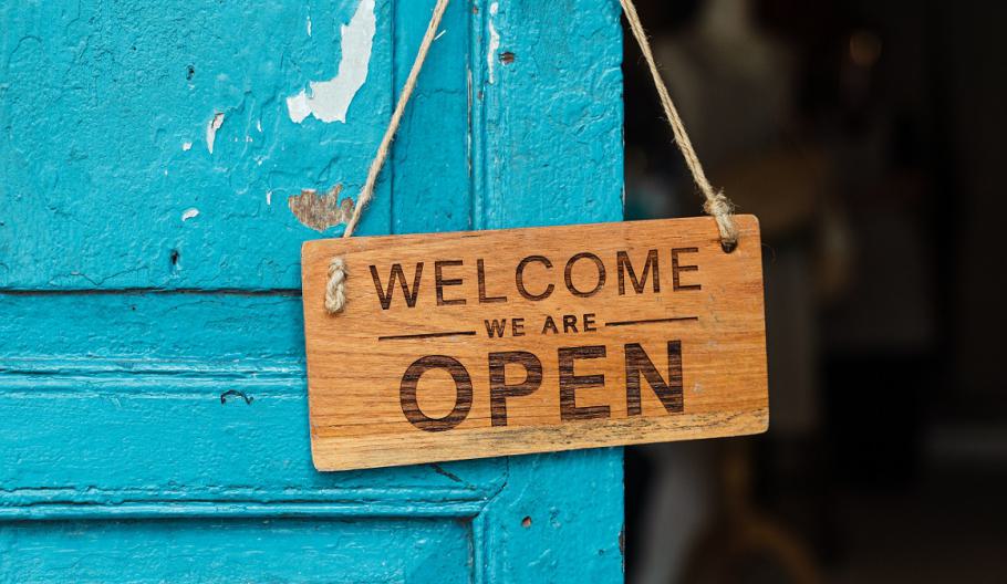 Image of a wooden business sign on a blue-painted door that says 'Welcome we are open